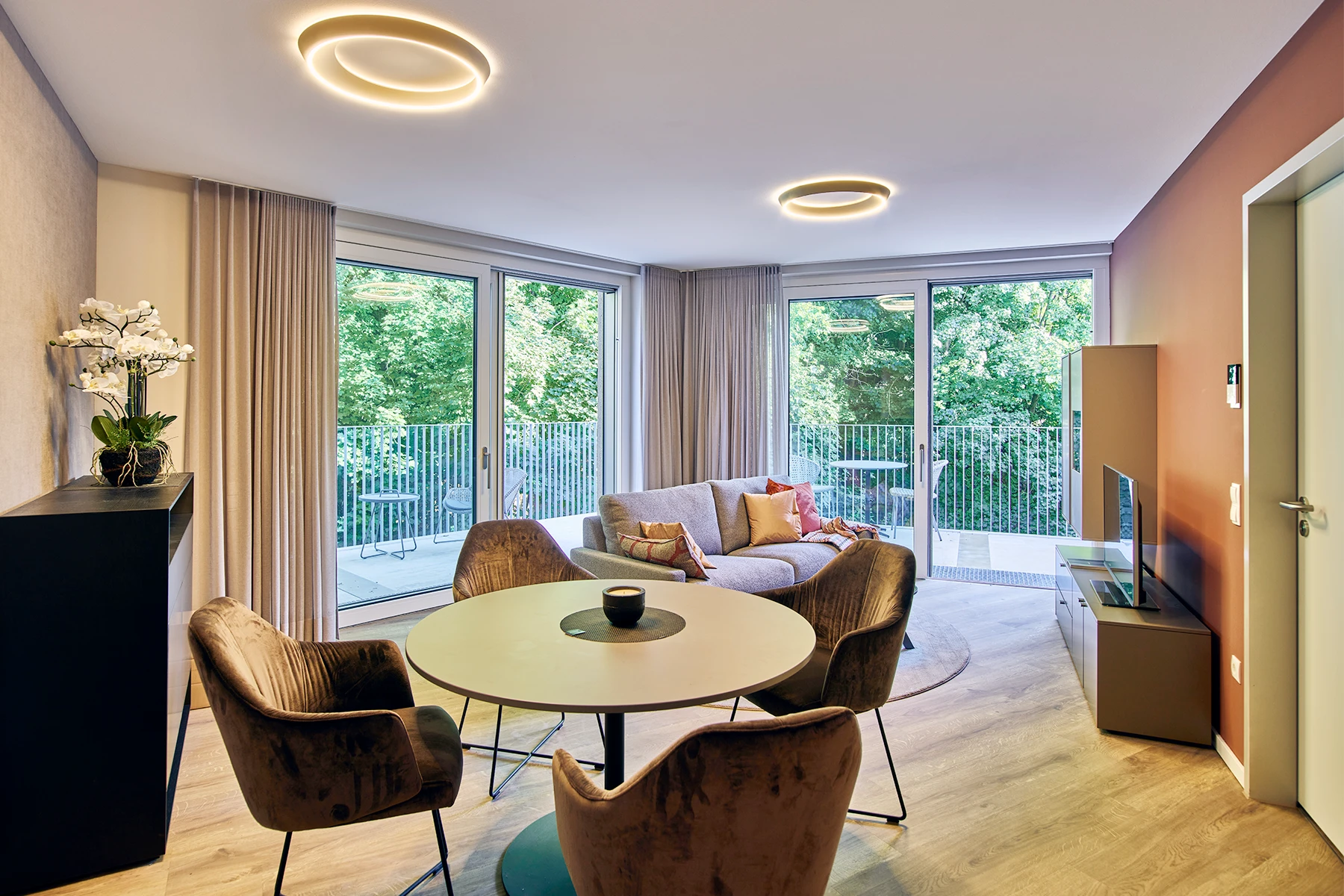 Betreutes Wohnbereich mit Essplatz, Couch und Zugang zur Terrasse mit bodentiefen Fenstern